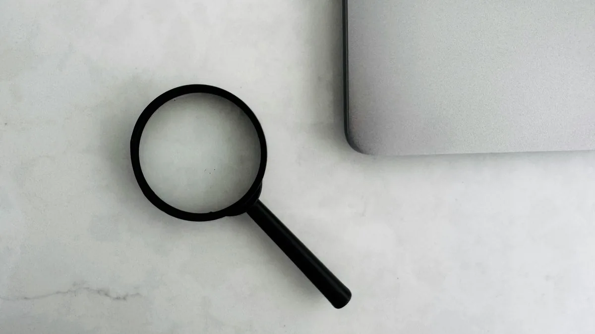 Profissional analisando documentos de marca com lupa em ambiente de trabalho focado