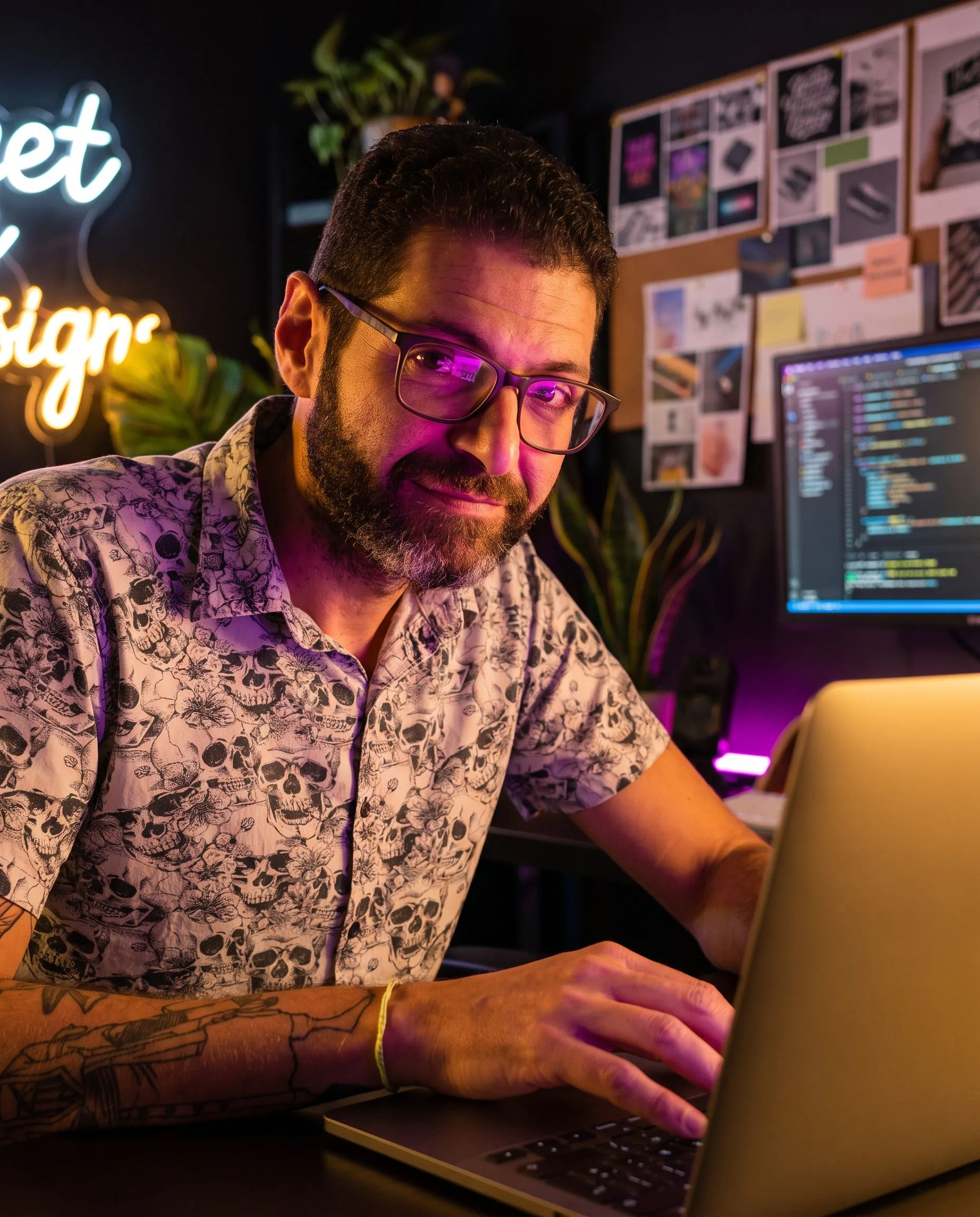 Gui Loureiro no próprio estúdio-laboratório à noite, construindo no laptop com código na tela e neon ao fundo